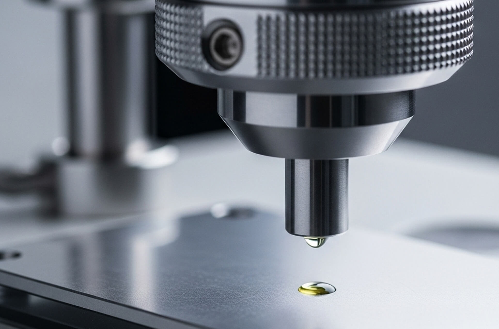 A drop of oil on the tip of a machine spindle above a metal plate